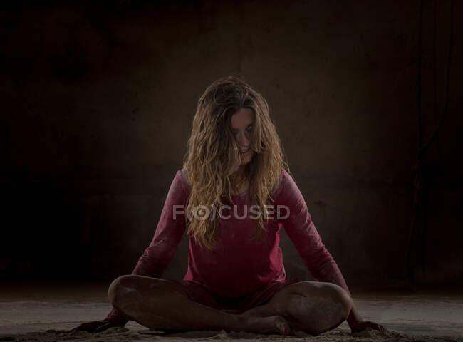 Mujer joven en pose de loto entre la arena en la oscuridad - foto de stock