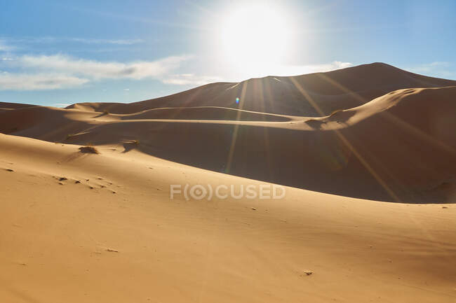 Desierto con colinas de arena y cielo azul con sol en Marrakech, Marruecos - foto de stock