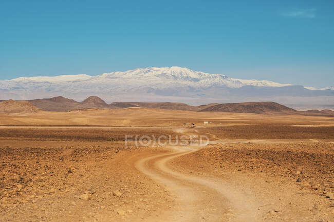 Живописный вид на сельскую дорогу между пустыней с дикими землями и голубым небом в Марракеше, Моро — стоковое фото