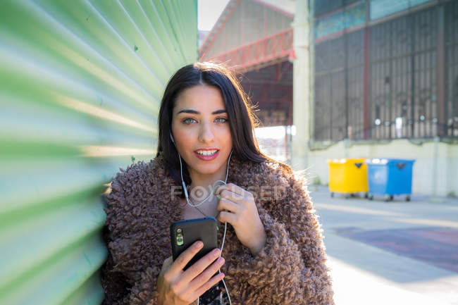 Trendfrau mit Smartphone in Wandnähe — Stockfoto