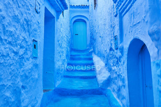 Increíble vista de camino a puerta entre antiguos edificios de piedra azul en Marrakech, Marruecos - foto de stock