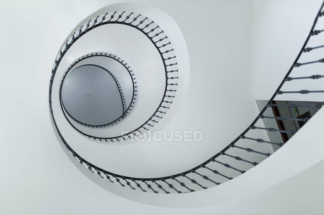 Desde abajo modernas escaleras en espiral con barandilla negra en el interior - foto de stock