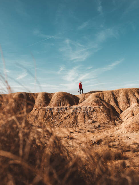 Vista à distância do viajante em pé no topo do desfiladeiro arenoso sob o céu azul — Fotografia de Stock