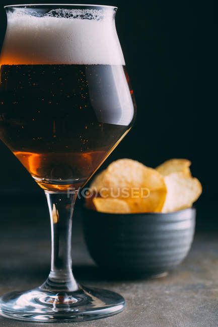 Glass of beer and chips on dark grunge background — Stock Photo