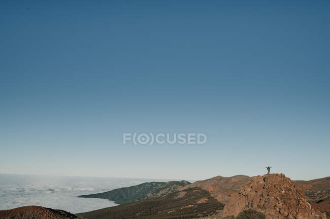 Неузнаваемый турист, стоящий на вершине холма вдали в безоблачный день — стоковое фото