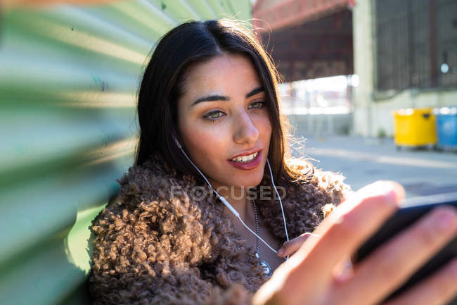 Mulher na moda com smartphone perto da parede — Fotografia de Stock