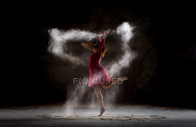 Jovem dançando e usando pó na escuridão — Fotografia de Stock