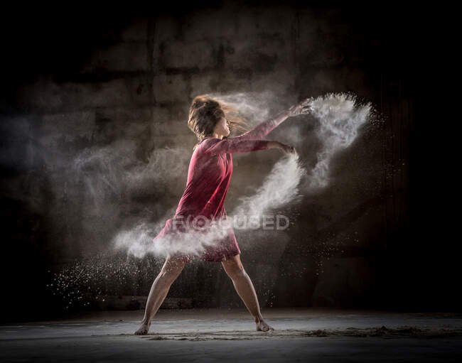 Jeune femme dansant et utilisant la poudre dans l'obscurité — Photo de stock