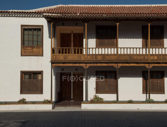 Светлый винтажный дом с деревянными окнами и балконом в солнечный день — стоковое фото