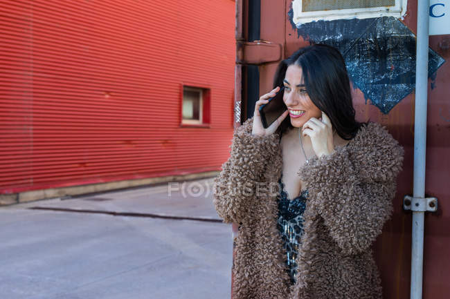 Mulher na moda com smartphone perto da parede — Fotografia de Stock