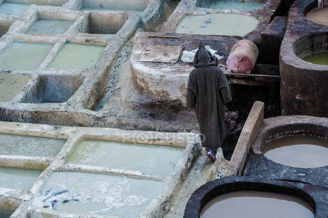From above back view of human between grunge stone containers with dye liquid in Marrakesh, Morocco — Stock Photo