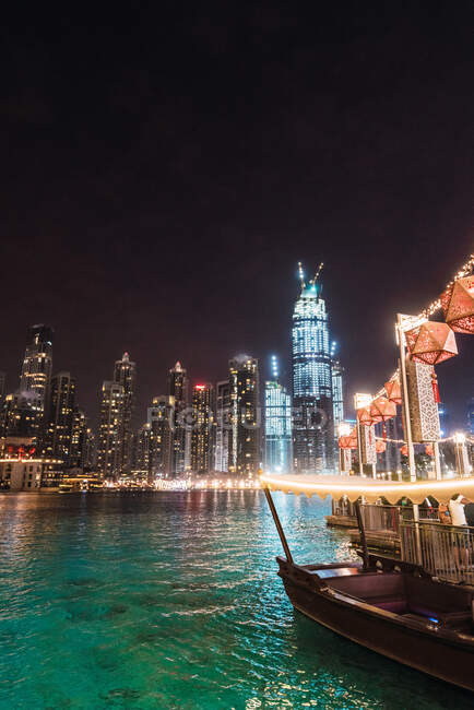 Лодка и набережная в ночном мегаполисе — стоковое фото