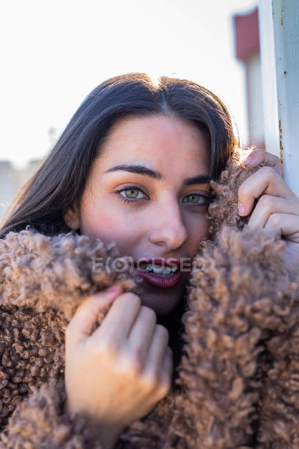Mujer alegre envolviendo en abrigo en la calle - foto de stock