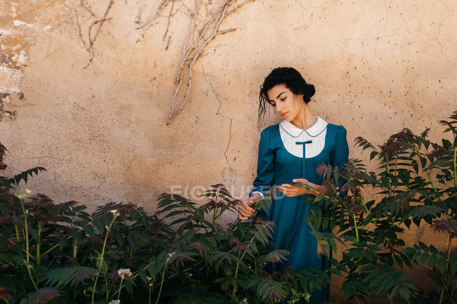 Attraente donna araba in abito tra le piante vicino al muro — Foto stock