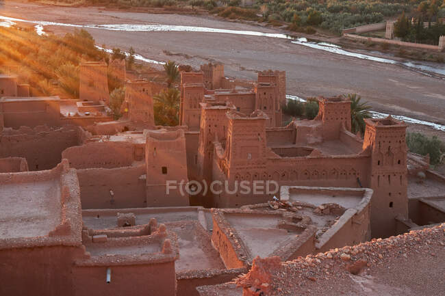 Dall'alto della città vecchia con costruzioni in pietra vicino allo stretto fiume tra il deserto e la luce del sole a Marrakech, Marocco — Foto stock