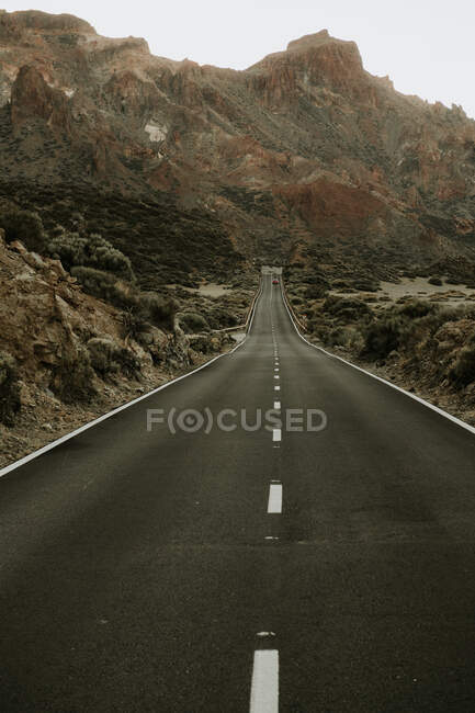 Vue en perspective de la route asphaltée dans la terre ferme menant aux montagnes — Photo de stock