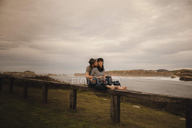 Young couple playing on hand drum near coast of sea and cloudy sky — Stock Photo