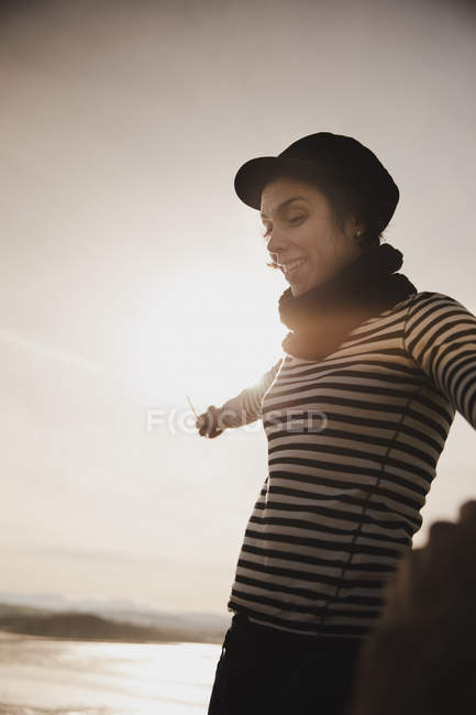 Elegante donna in berretto sulla costa vicino al mare ondulante — Foto stock