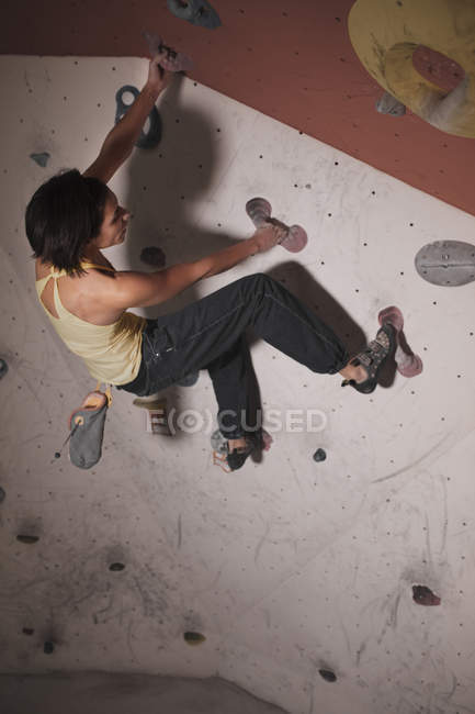 Задний вид женщины в спортивной одежде, тренирующейся на скалолазании с трюками в тренажерном зале — стоковое фото