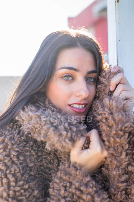 Cheerful woman wrapping in coat on street — Stock Photo