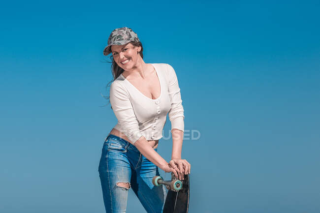 Щаслива пані з довгою дошкою, що стоїть на асфальтній дорозі. — стокове фото