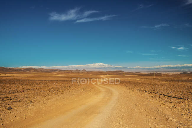 Pintoresca vista de la ruta rural entre el desierto con tierras salvajes y el cielo azul en Marrakech, Marruecos - foto de stock