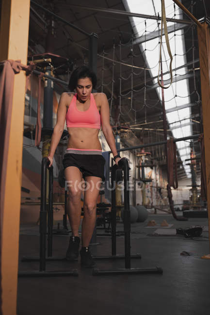 Mulher em sportswear fazendo puxar para cima exercícios em barras paralelas em grande ginásio — Fotografia de Stock