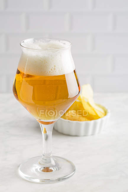 Glass of beer and potato chips on white background — Stock Photo