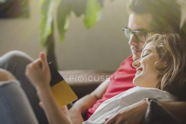 Allegro sognante uomo e donna sdraiati sul divano e brochure di lettura — Foto stock