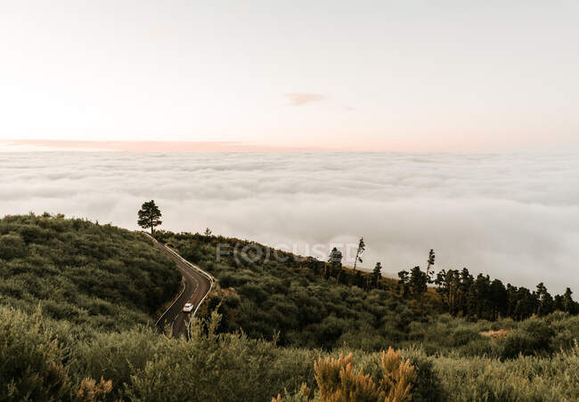De dessus la route asphaltée sur la colline verte et vue sur le paysage nuageux — Photo de stock