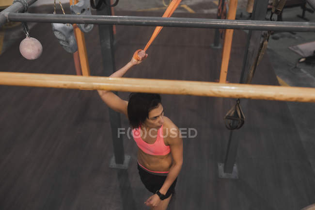 Mujer en ropa deportiva haciendo ejercicios de pull up en barra horizontal en el gimnasio - foto de stock