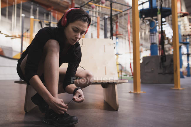 Вид сбоку на женщину в наушниках, слушающую музыку и стирающую обувь в спортзале — стоковое фото
