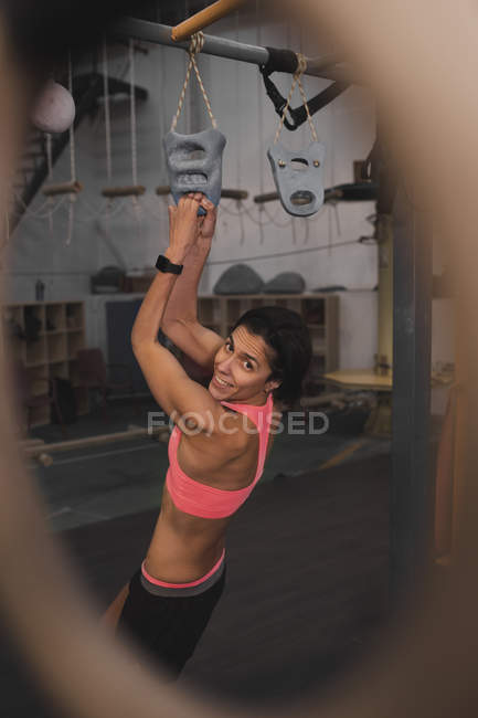 Жінка з спортивного одягу робить вправи на горизонтальному брусі в спортзалі — стокове фото
