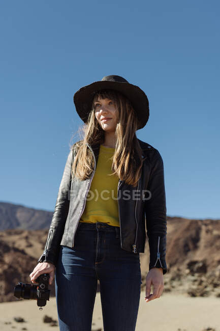 Женщина-фотограф стоит с камерой и смотрит на холмы в пустыне — стоковое фото