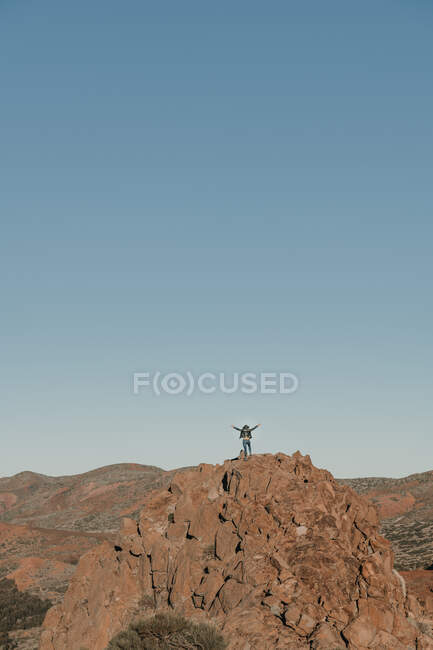 Turista irreconocible de pie en la cima de la colina lejos en un día sin nubes - foto de stock
