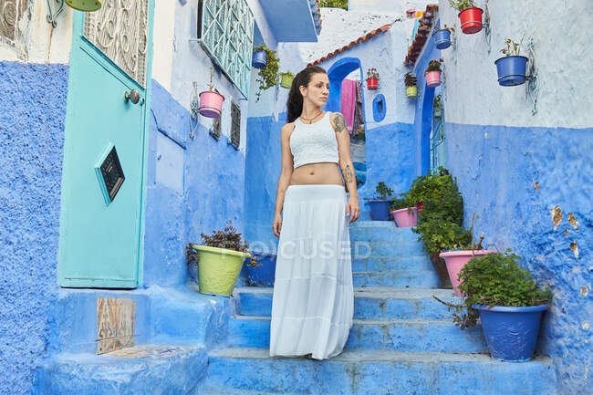 Красивая женщина, идущая между синими домами в Марракеше — стоковое фото