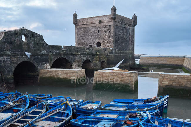 Blue fishing boats moored at historic construction in Essaouira, Morocc — Stock Photo