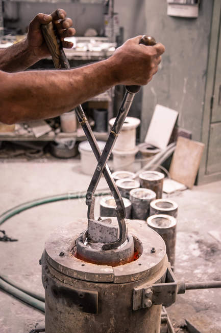 Männliche Hände mit Hebezangen nehmen Metallprodukte aus Tiegel auf kleiner Gießerei — Stockfoto