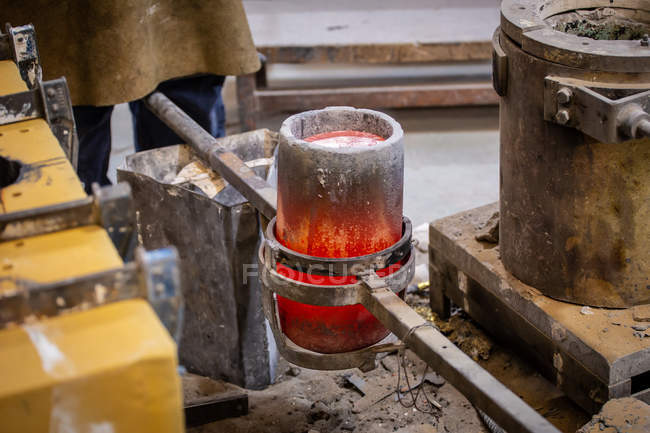 Beine eines Mannes stehen in der Nähe von Schmelztiegel mit geschmolzenem Stahl auf wenig Gießerei — Stockfoto