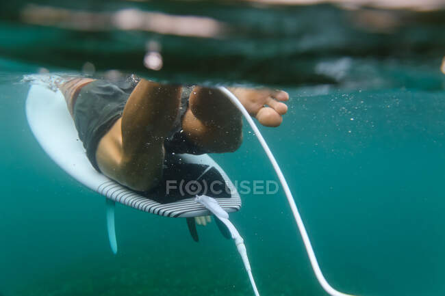 Back view of crop male floating on surf board in azure water of sea on Bali, Indonesia — Stock Photo