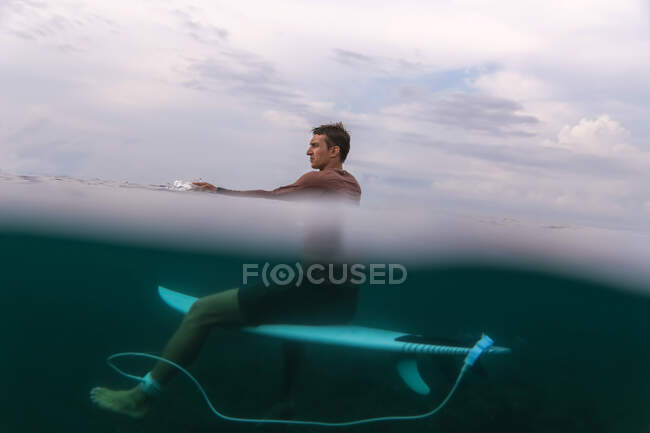 Side view of male floating on surf board in azure water of sea on Bali, Indonesia — Stock Photo
