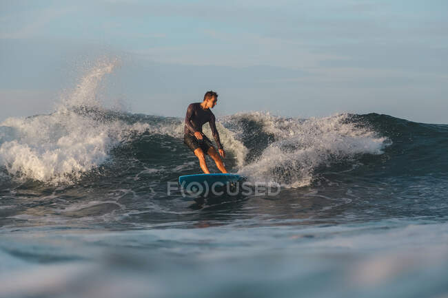 Male surfing between waving water of sea with splashes in Bali, Indonesia — Stock Photo