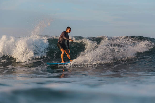 Hombre surfeando entre olas de agua de mar con salpicaduras en Bali, Indonesia - foto de stock