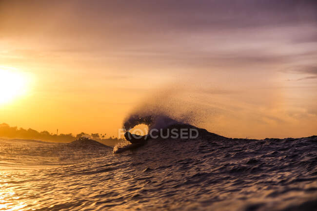 Side view of male floating on surf board between water of sea and cloudy heaven on Bali, Indonesia — Stock Photo