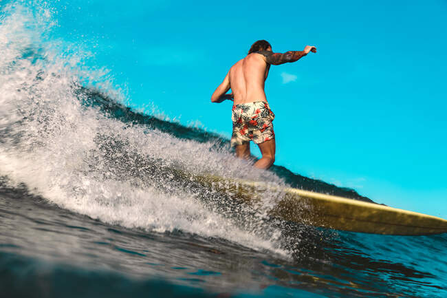 Back view of male surfing between waving water of sea with splashes in Bali, Indonesia — Stock Photo