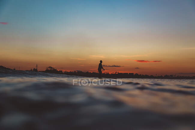 Увечері на Балі (Індонезія) видніється вид на силует самця з веслом на дошці для серфінгу між водою моря та небом. — стокове фото