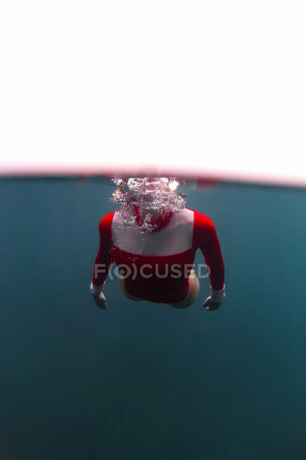 Anonymous female in red swimsuit diving in blue water of sea on Bali, Indonesia — Stock Photo