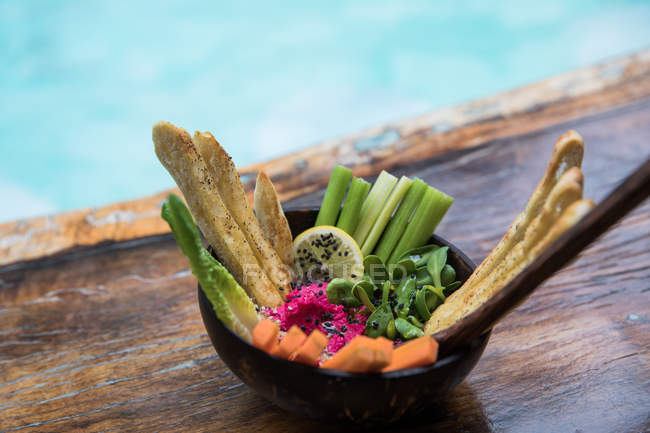 Миска зі свіжих овочів і хлібних паличок на дерев'яному столі — стокове фото