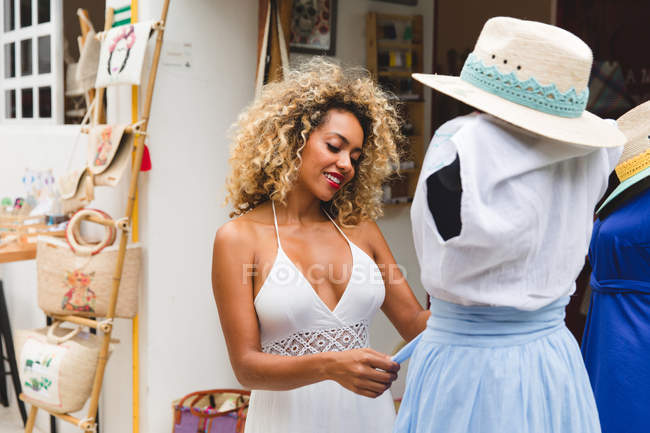 Стильная черная молодая женщина выбирает ткань на вешалке в магазине — стоковое фото