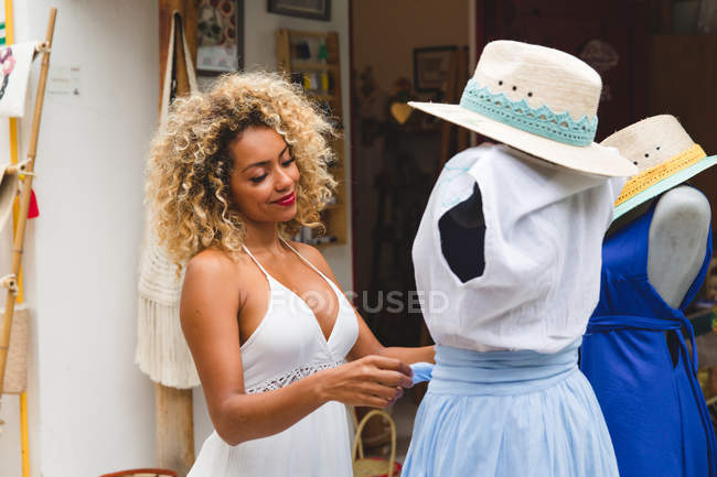 Elegante mujer joven negro elegir tela en la percha en la tienda - foto de stock
